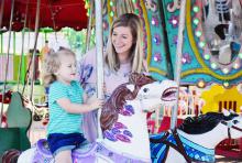 Raden Kennedy watches with joy as her two-year old daughter Kate Kennedy rides the Merry-Go-Round.